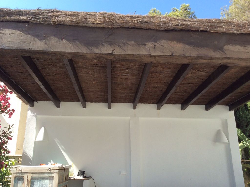 Pérgola rústica con techo de brezo en doble capa y plástico para evitar el paso de agua